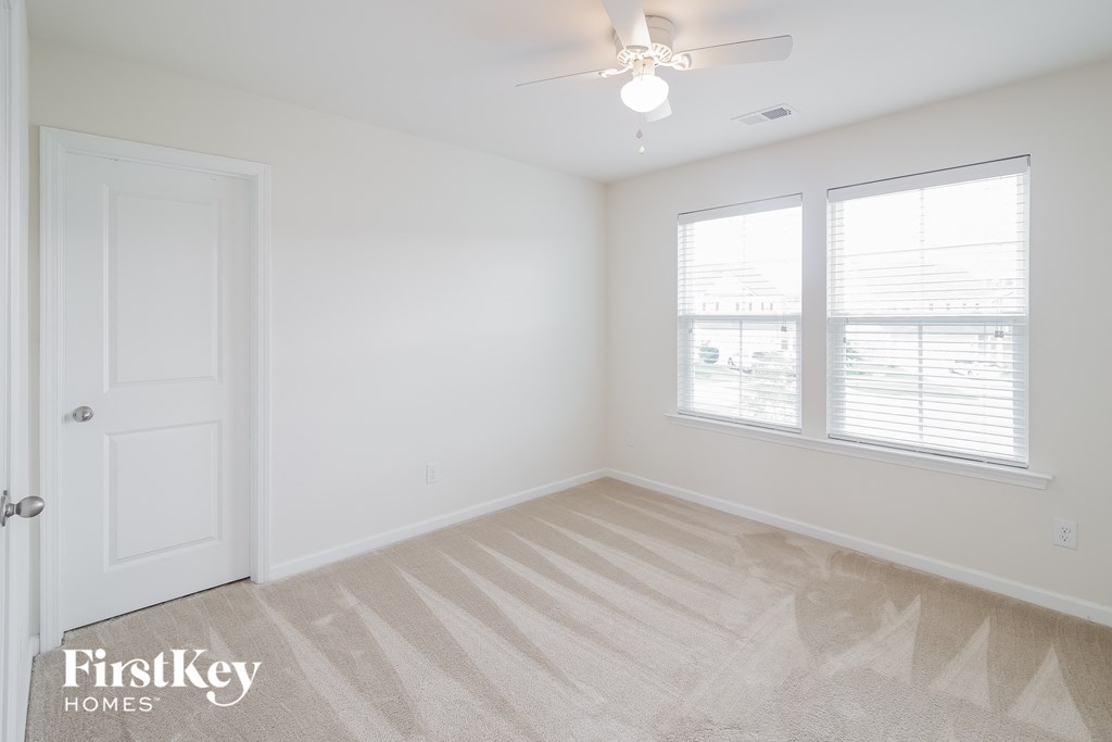 A room with a carpeted floor and a ceiling fan.