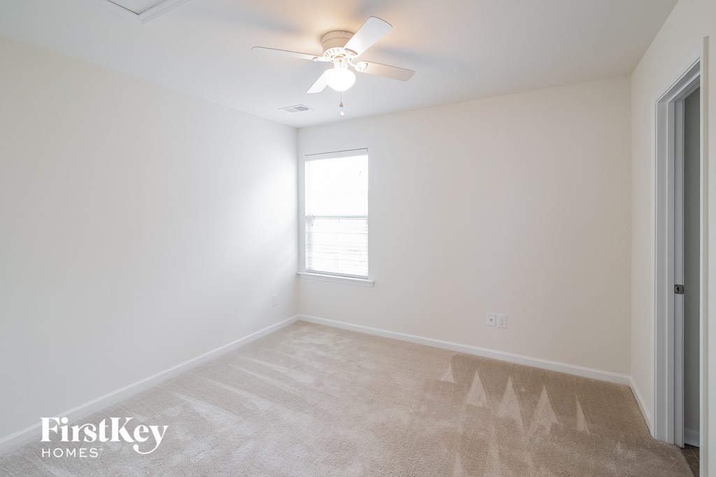 A room with a carpet floor and a ceiling fan.