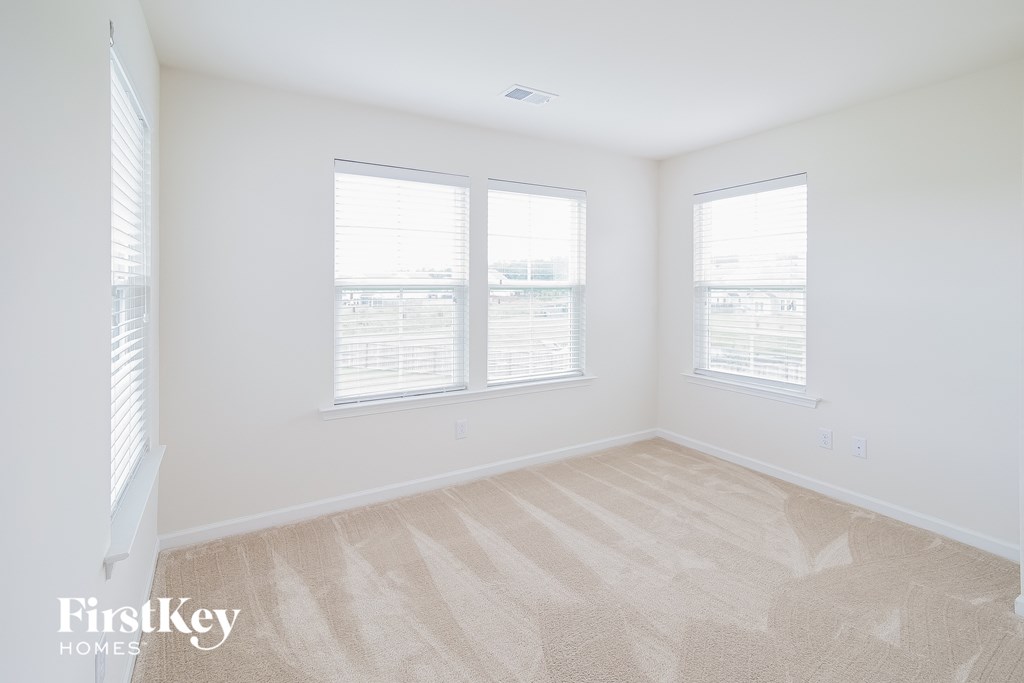 A room with a carpeted floor and two windows.