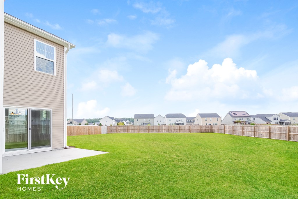 A house with a fence and a grassy field in the foreground.
