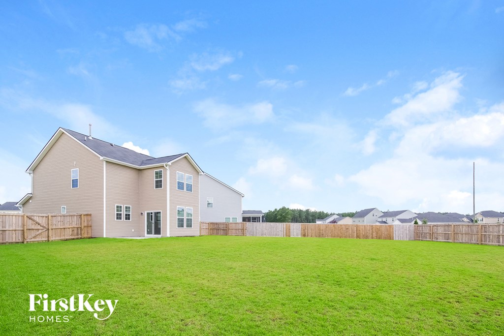 A house with a fence and a grassy field in front of it.