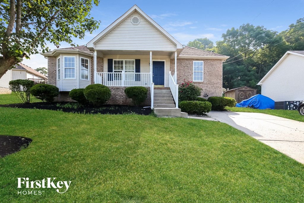 A house with a well-maintained lawn and a blue tarp in the background.