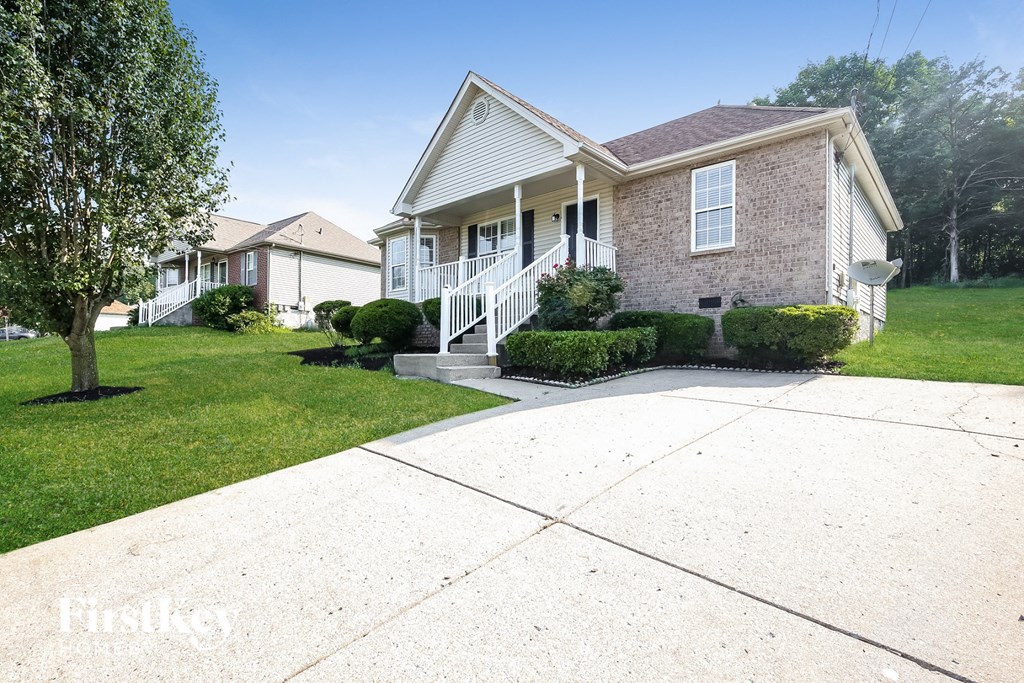 A house with a white front porch and a tree in front of it.