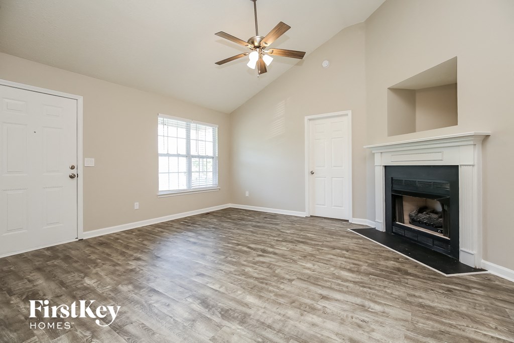 A spacious room with a fireplace and a ceiling fan.