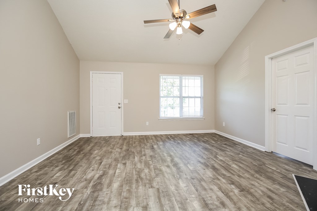 A room with a ceiling fan and wooden flooring.