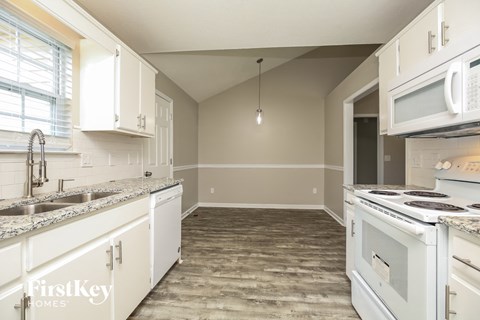 A kitchen with white cabinets and a wooden floor.