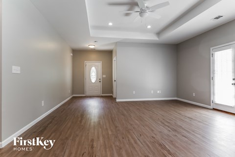 A spacious room with wooden floors and a ceiling fan.
