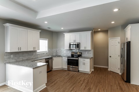 A kitchen with white cabinets and a refrigerator.