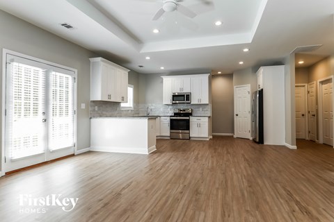 A spacious kitchen with wooden floors and white cabinetry.