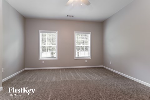 A room with two windows and a carpeted floor.