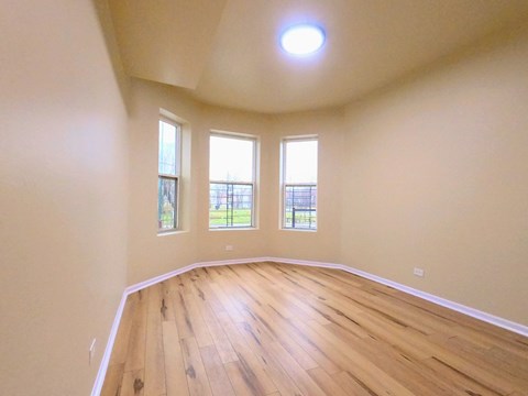 an empty living room with wooden floors and windows
