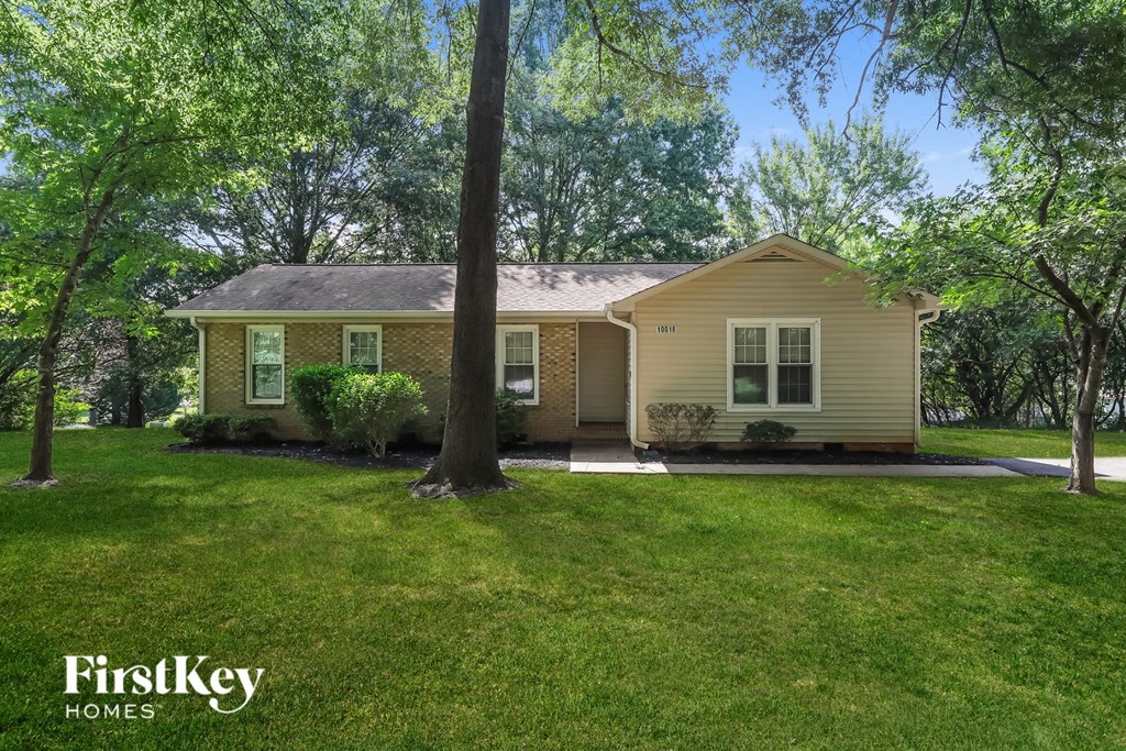 a small yellow house with a lawn and trees