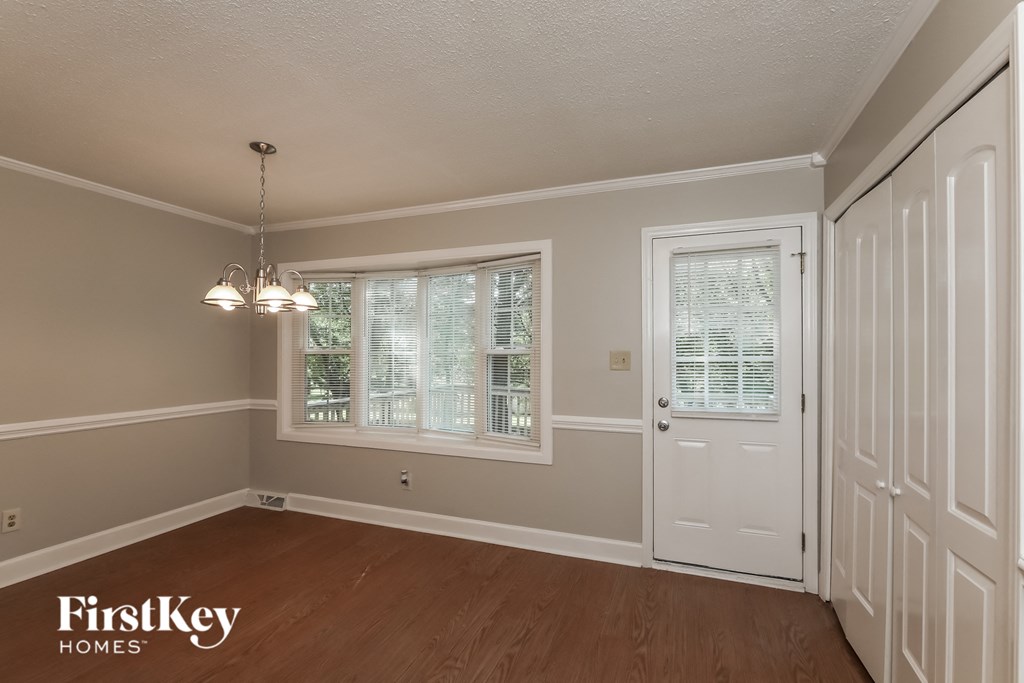 the dining room of a house with a white door and two windows