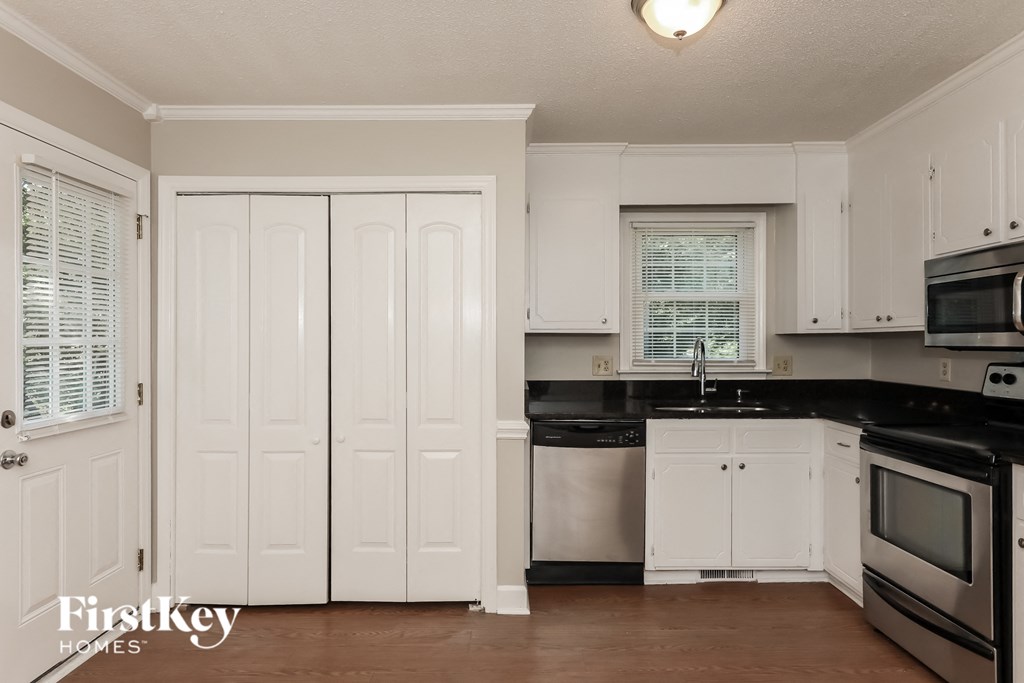 a kitchen with white cabinets and black counter tops and a black and white