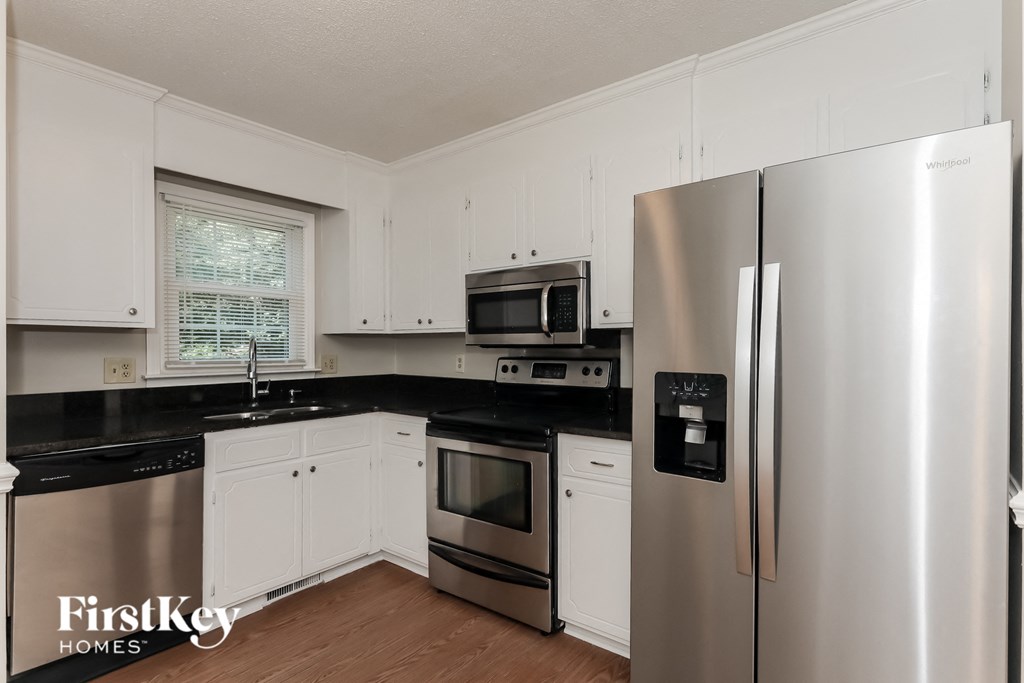 a kitchen with stainless steel appliances and black counter tops and white cabinets