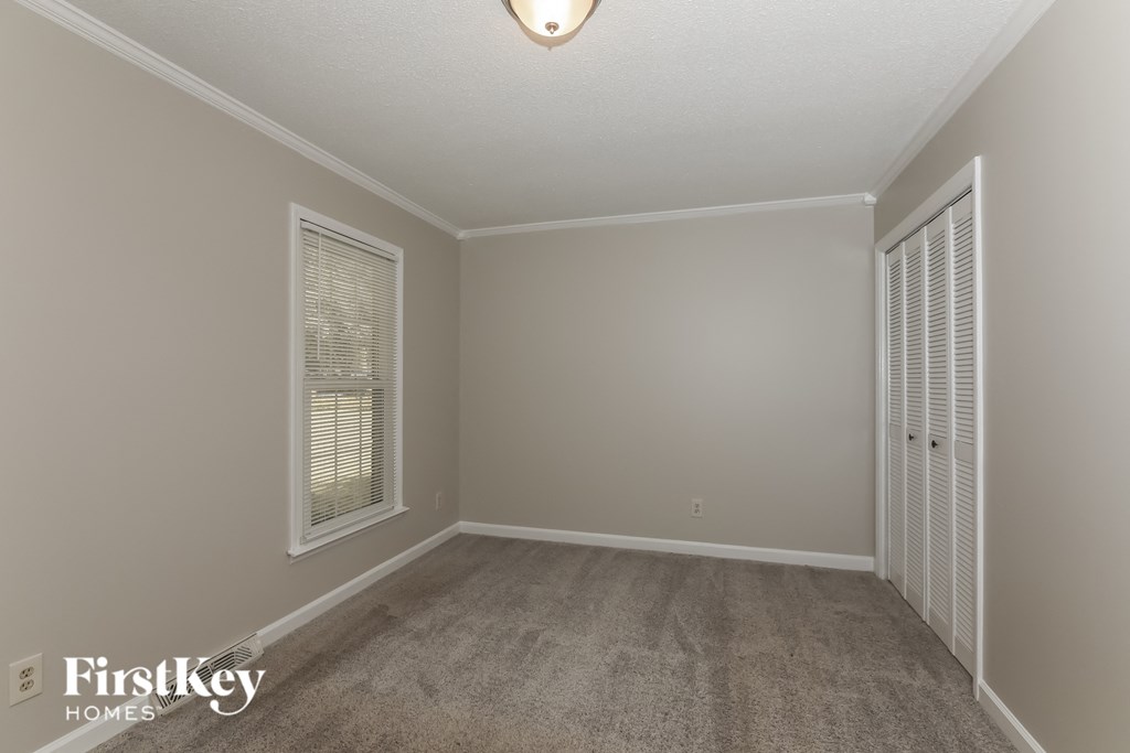 a empty living room with a carpeted floor and two windows
