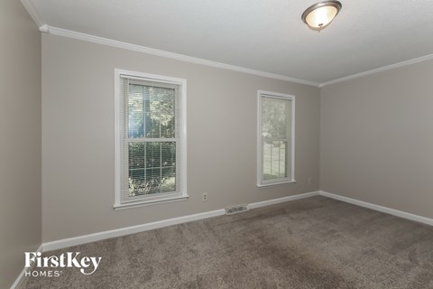 the living room of a house with two windows and a carpet