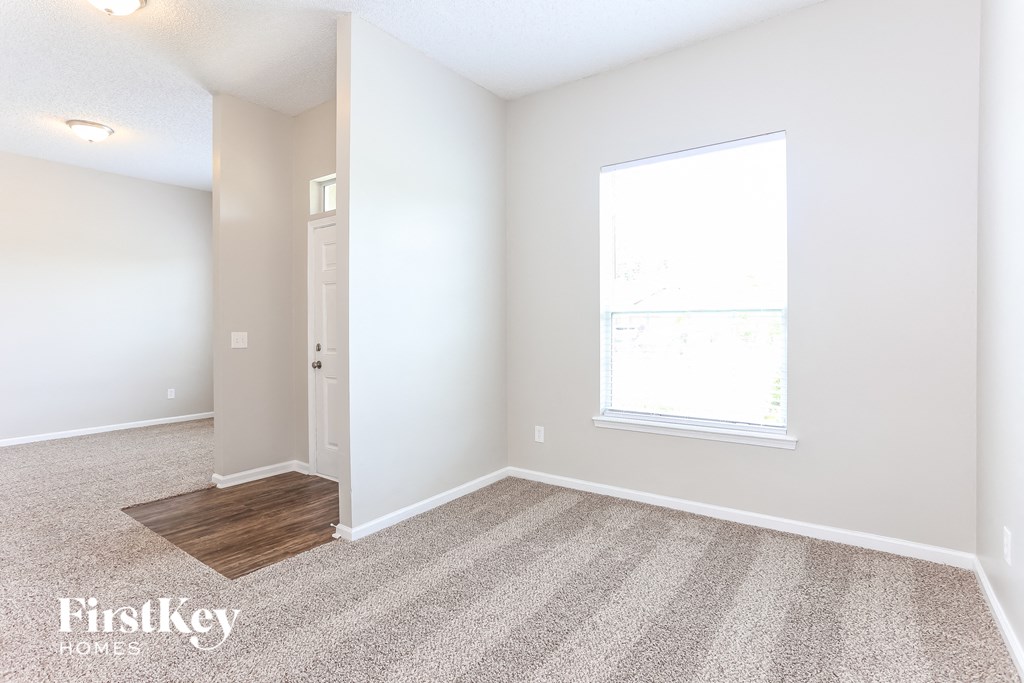 a bedroom with a window and a carpeted floor