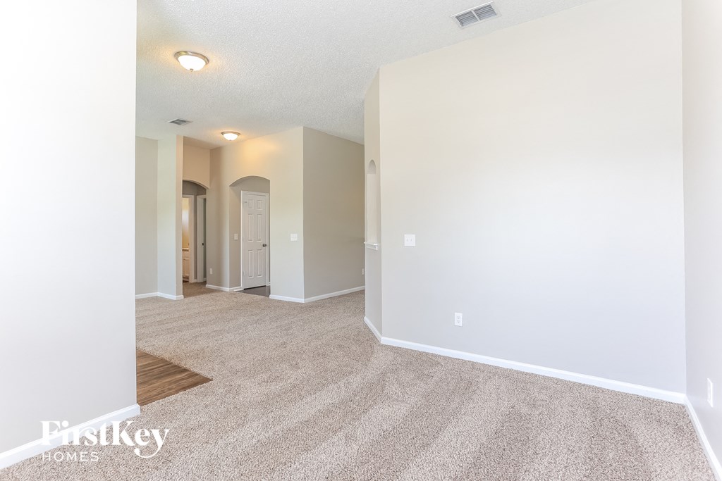 the living room and dining room with carpeting and white walls
