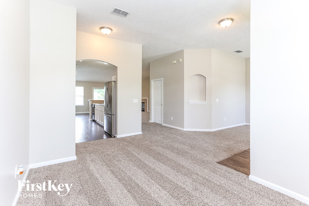 the living room and dining room with white walls and carpeting