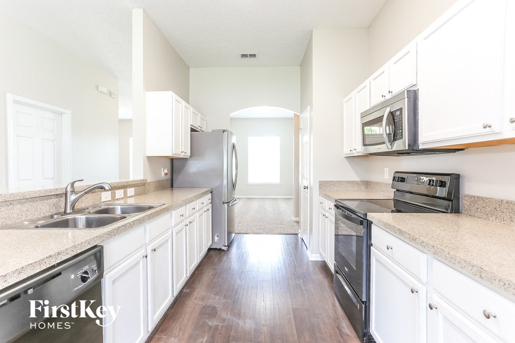 an empty kitchen with white cabinets and stainless steel appliances