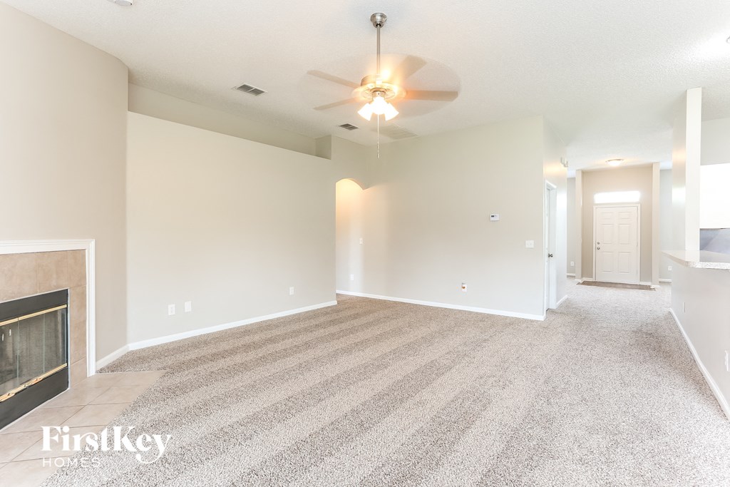 an empty living room with a ceiling fan and a fireplace