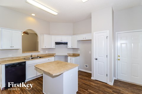 A kitchen with white cabinets and a wooden island.