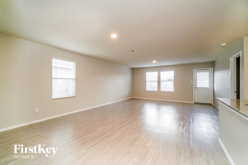 A spacious room with wooden floors and two windows.