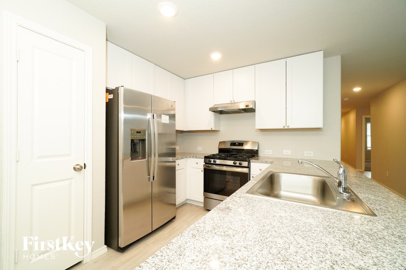 A kitchen with a stainless steel refrigerator, oven, and sink.