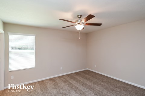 the spacious living room with ceiling fan and carpet