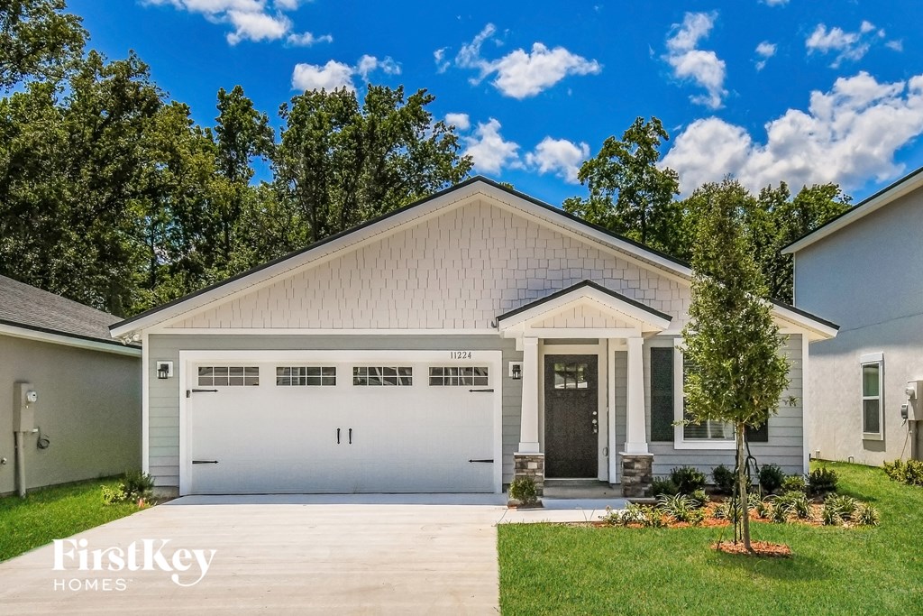 a white house with a garage door and a lawn
