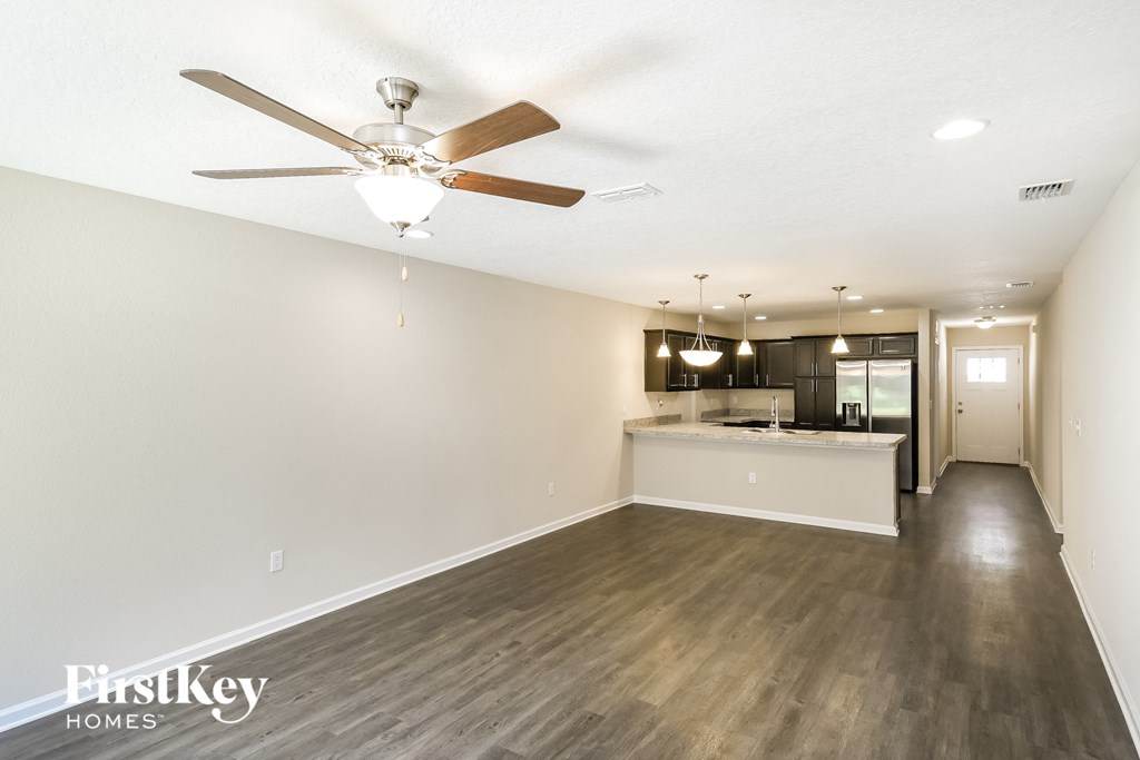 an empty kitchen and living room with a ceiling fan
