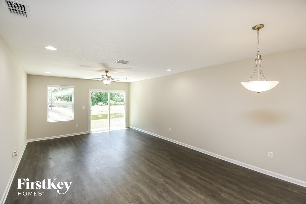 an empty living room with wood floors and a ceiling fan