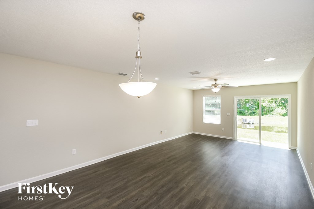 an empty living room with wood floors and a ceiling fan