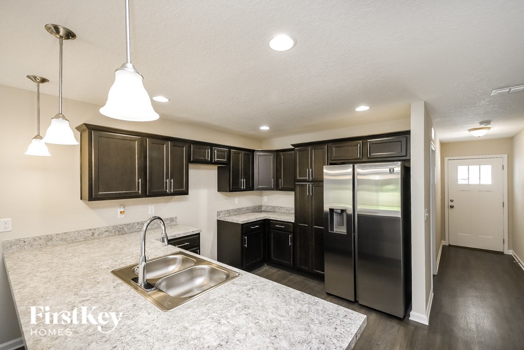 a kitchen with black cabinets and a stainless steel refrigerator