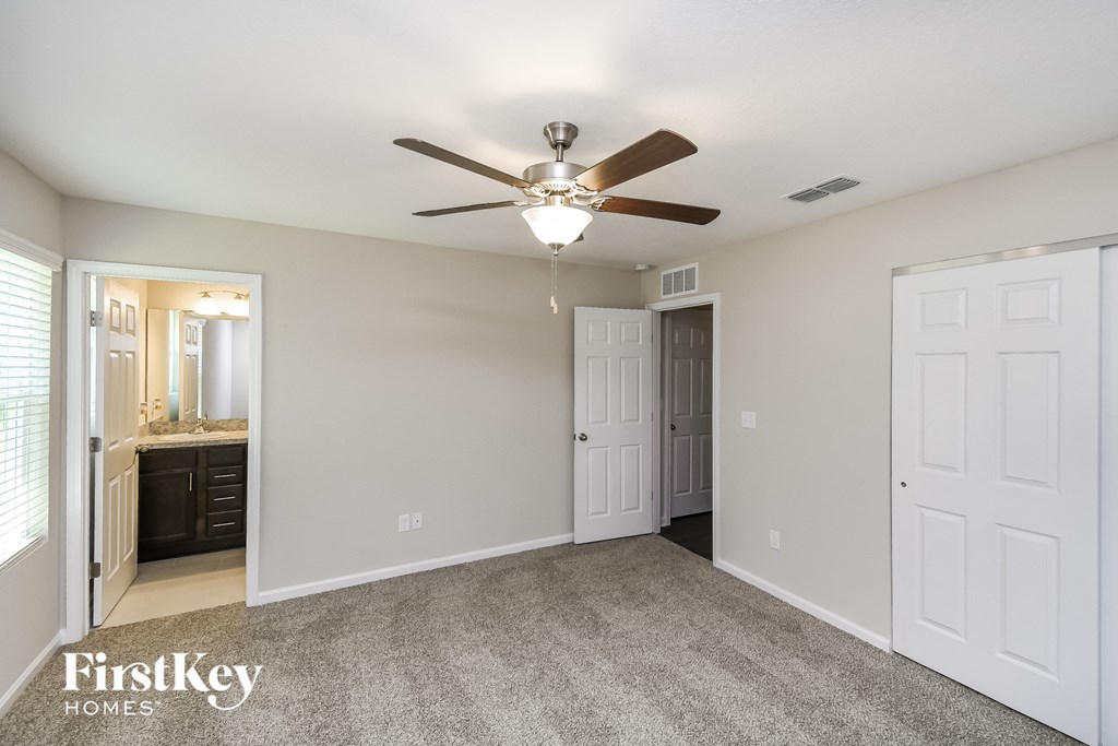 an empty living room with a ceiling fan and a bathroom