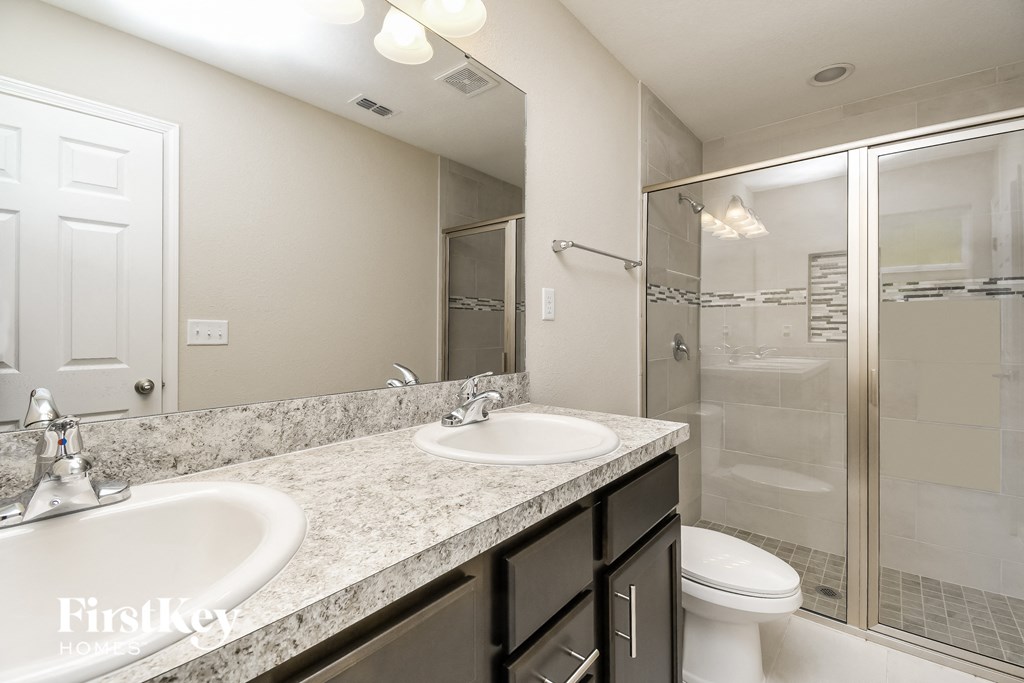 a bathroom with two sinks and a shower and a toilet