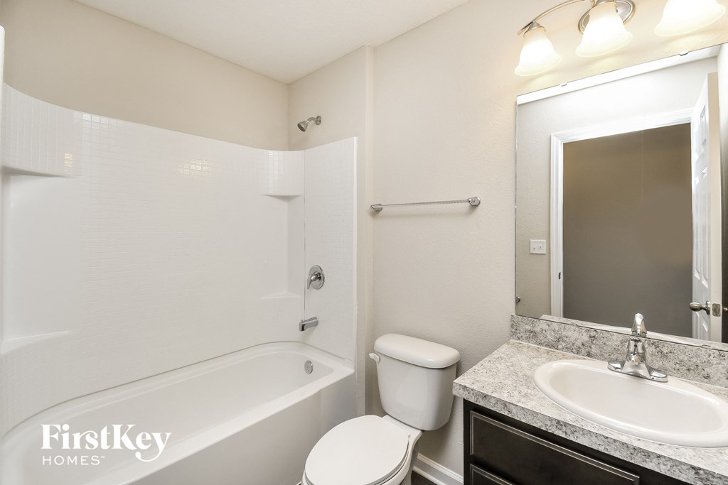 a bathroom with a toilet sink and tub and a mirror