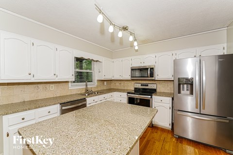 A kitchen with a granite counter top and stainless steel appliances.