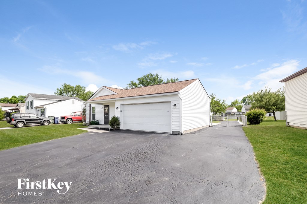 a white garage with a white house on the side of a driveway