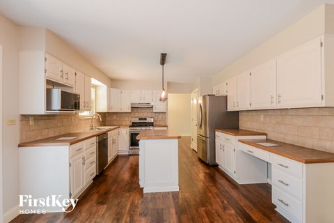 A kitchen with white cabinets and wooden floors.