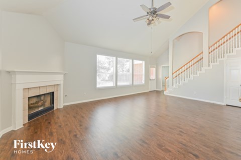 A spacious living room with a fireplace and a staircase.