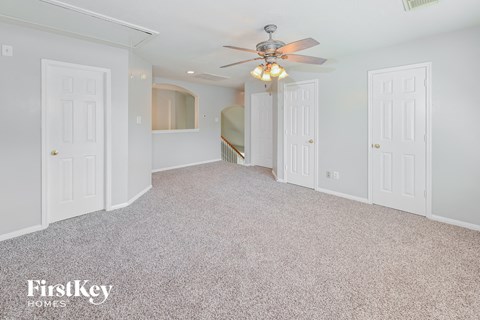 A spacious room with a ceiling fan and carpeted floor.