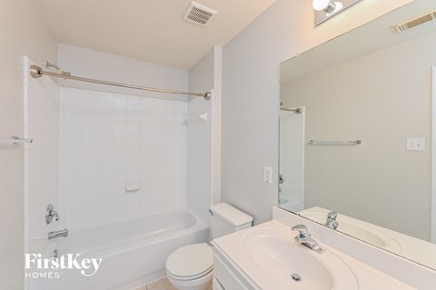 A white bathroom with a tub, toilet and sink.