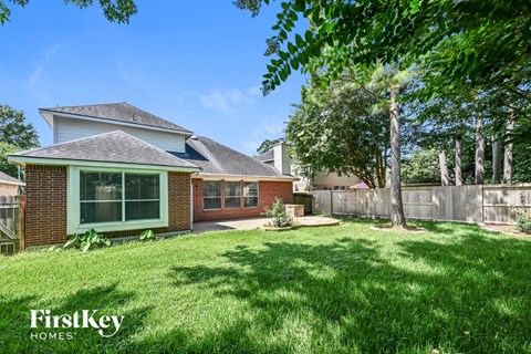 A house with a green lawn and trees in the background.