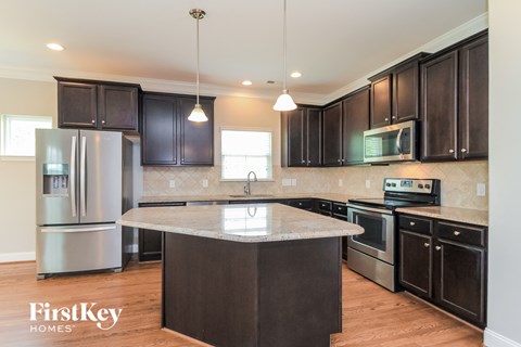 a kitchen with black cabinets and stainless steel appliances and a marble counter top