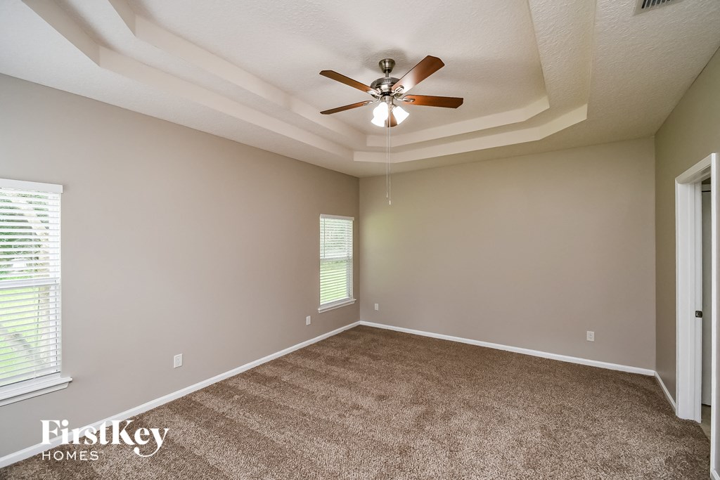 an empty living room with carpet and a ceiling fan