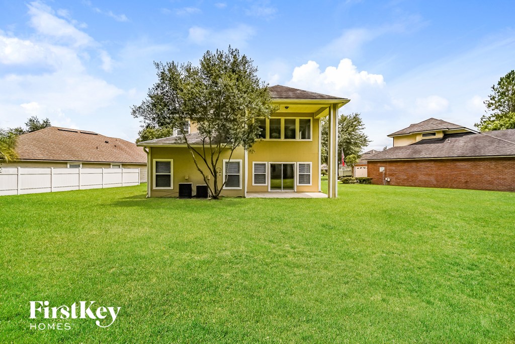 a yellow house with a lawn and a white fence