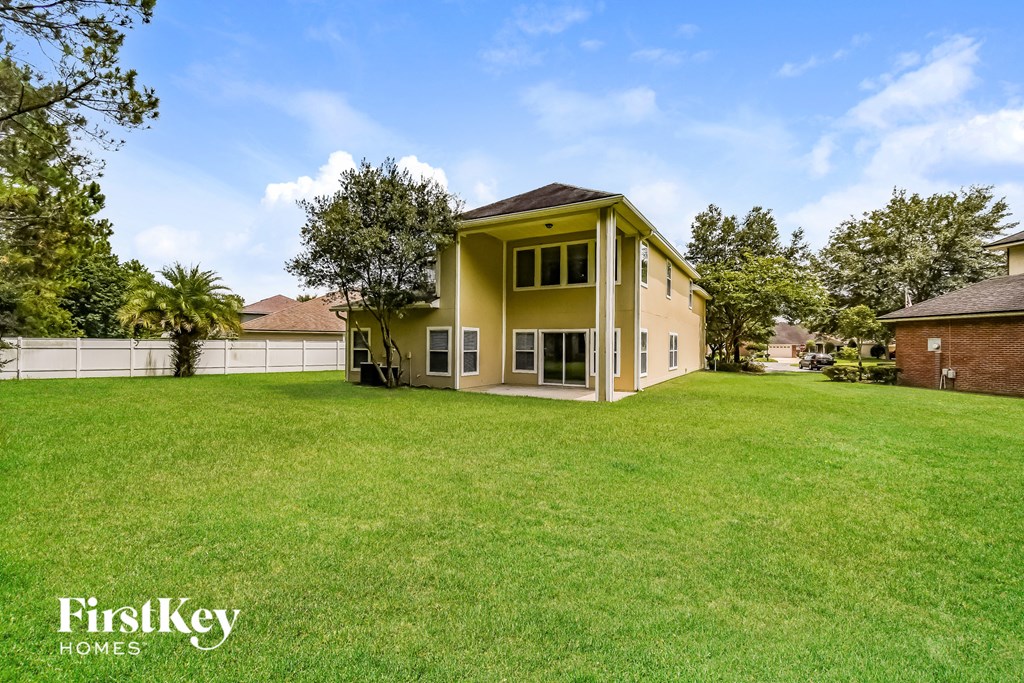 a yellow house with a big yard and a fence