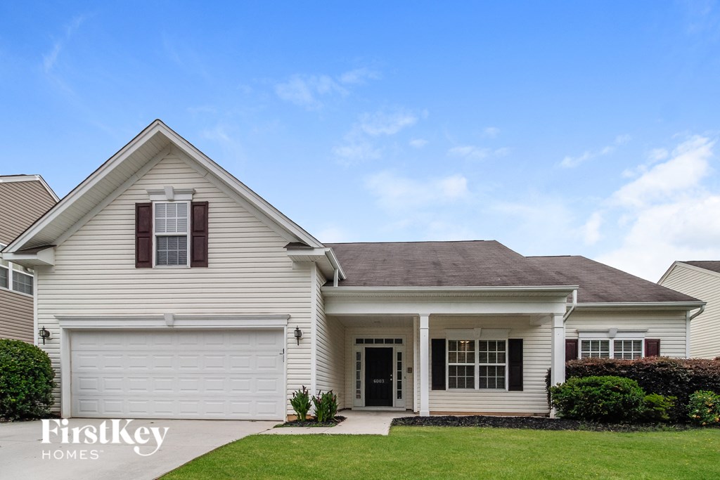 A house with a garage door and a front door is for sale.